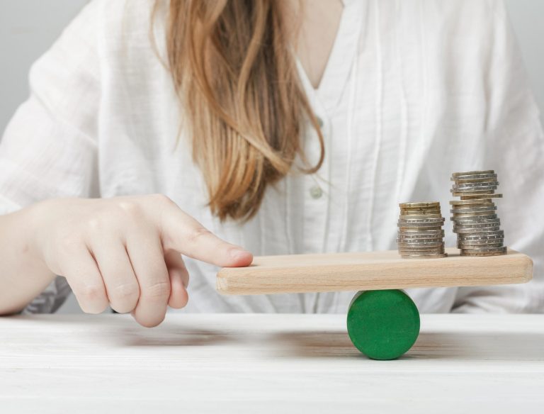 mujer-sosteniendo-su-dedo-en-equilibrio-con-las-monedas